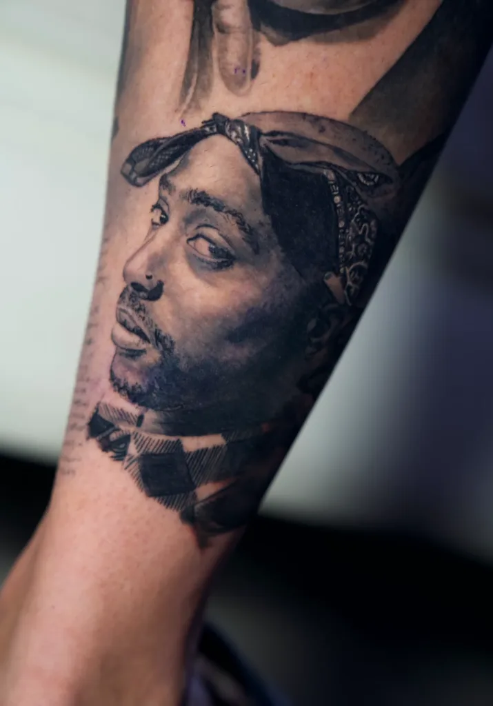 an image of tupac tattooed on a man's arm showcasing a portrait tattoo artist in Miami